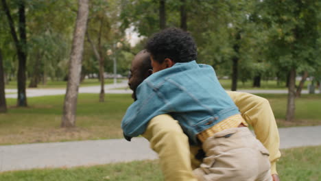 African-American-Man-Giving-Piggyback-Ride-to-Little-Son-in-Park